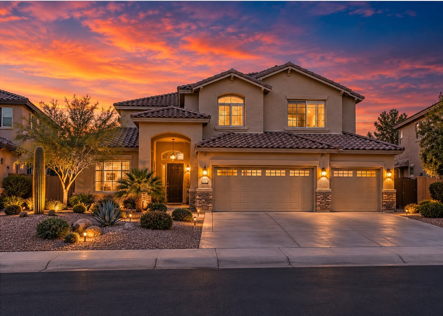 Two-story East Valley home at dusk with glowing windows and landscape lighting under an orange and blue sunset sky